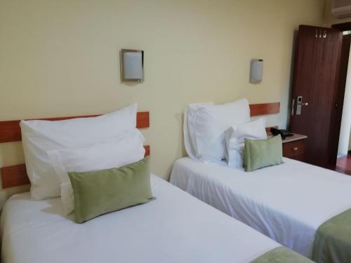 two beds with white sheets and green pillows in a room at Adelaide Hotel in Geres