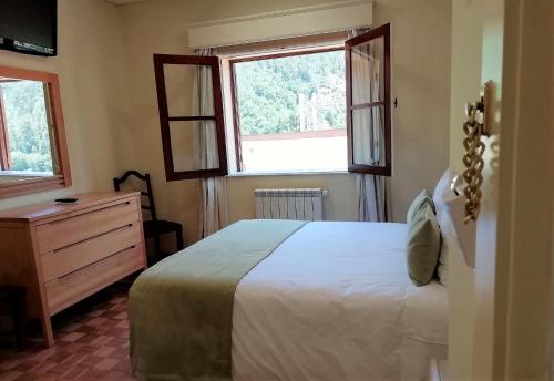 a bedroom with a bed and a dresser and two windows at Adelaide Hotel in Geres