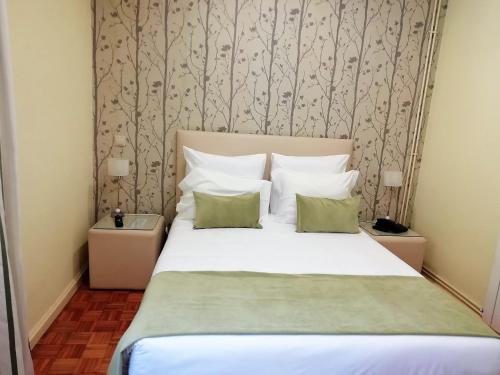 a bedroom with a bed with white sheets and green pillows at Adelaide Hotel in Geres