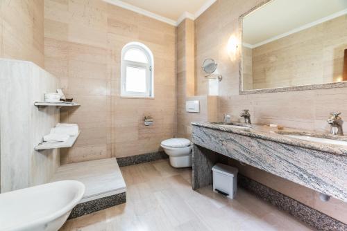 a bathroom with a sink and a toilet and a mirror at Grand Hotel Palladium Santa Eulalia del Río in Santa Eularia des Riu