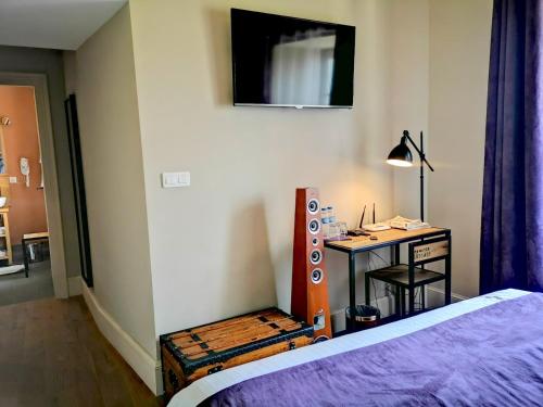 a bedroom with a bed and a desk with a lamp at Le relais des deux tours in Brémondans