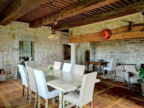 a dining room with a table and white chairs at Le relais des deux tours in Brémondans