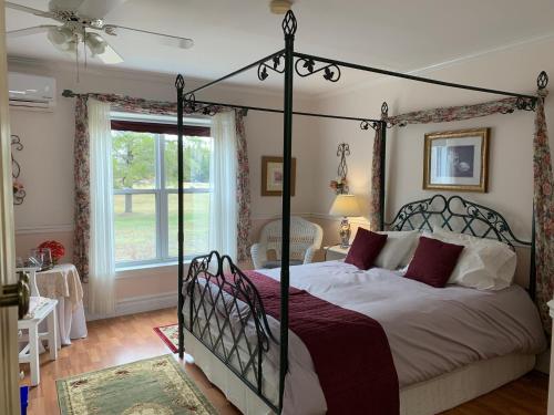 a bedroom with a canopy bed and a window at The Parrsboro Mansion Inn in Parrsboro
