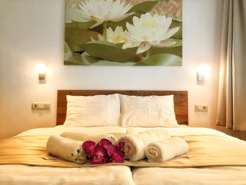 a bedroom with a bed with towels and flowers on it at Boró Apartman in Tiszafüred