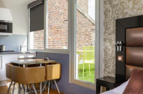une cuisine avec une table et des chaises à côté d'une fenêtre dans l'établissement Hôtel Ambre, à Paris