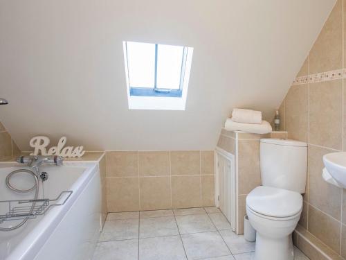 a bathroom with a toilet and a tub and a sink at Hen Stabl Llandwrog in Llandwrog