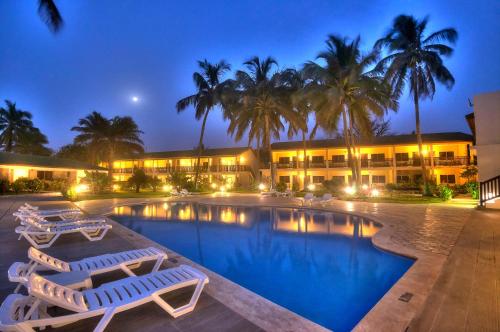 a resort with a swimming pool with chairs and palm trees at Sunset Beach Hotel in Sere Kunda NDing