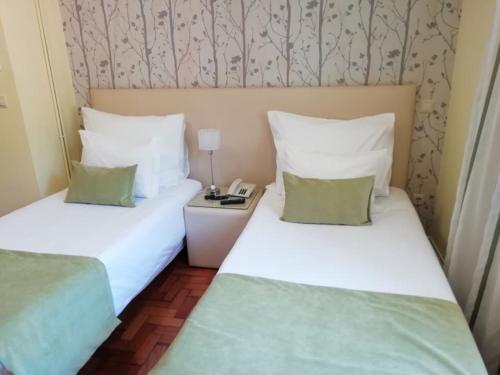 two twin beds in a room with a telephone at Adelaide Hotel in Geres