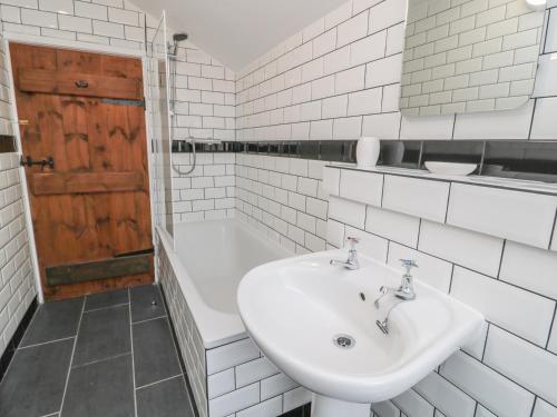 a white bathroom with a sink and a tub at Magpie Cottage in Wooler