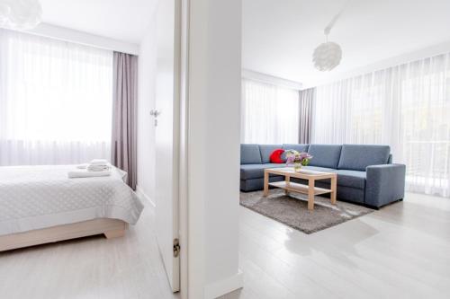 a bedroom with a bed and a couch and a table at Resort Apartamenty Klifowa Rewal 23 in Rewal