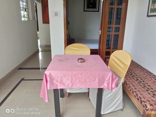 a table with a pink table cloth on it with two chairs at Taj Mahal Hotel in Cochin
