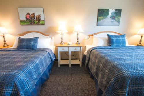 a hotel room with two beds and two lamps at Blue Gate Garden Inn in Shipshewana
