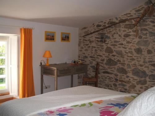 a bedroom with a stone wall with a bed and a desk at Chambres d'hôtes La Charrière in Cheffois