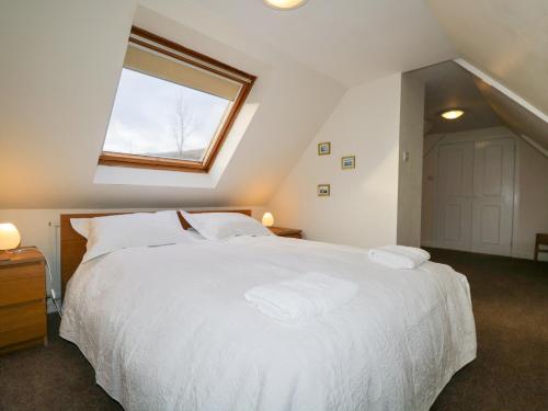 a bedroom with a large white bed with a window at Tigh Fasgaidh in Dornie