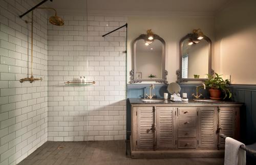 a bathroom with two sinks and two mirrors at Anantara Stanley & Livingstone Victoria Falls Hotel in Victoria Falls