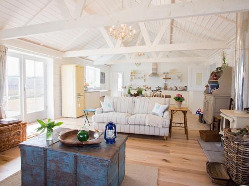 sala de estar con sofá blanco y mesa en Lligwy Beach Cottage, en Penrhos-Lligwy