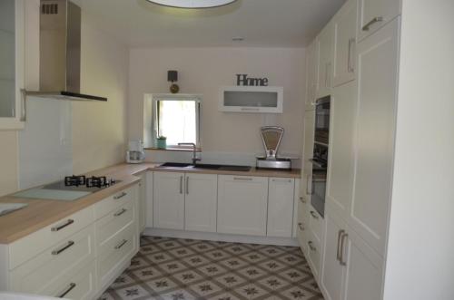 uma cozinha branca com armários brancos e um lavatório em La Remise 4 étoiles em Saint-Hilaire-de-Mortagne