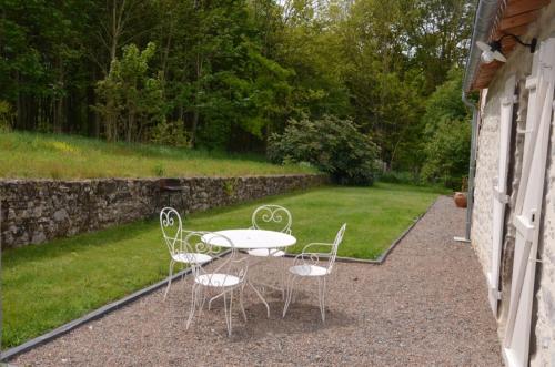 a table and chairs sitting on the side of a house at La Remise 4 étoiles in Saint-Hilaire-de-Mortagne