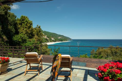 two chairs on a deck with a view of the ocean at Pelion BNB Luxury homes in Damouchari