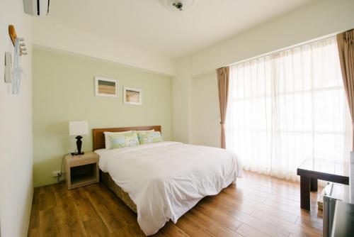 Un dormitorio con una cama blanca y una ventana. en He Sen B&B, en Kenting