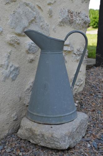 un vase métallique assis sur un rocher à côté d'un mur dans l'établissement La Remise 4 étoiles, à Saint-Hilaire-de-Mortagne