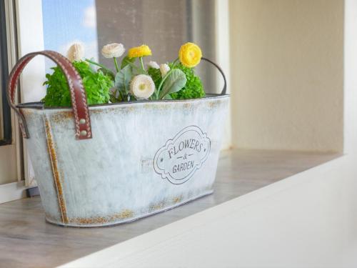 a metal bucket with flowers in it sitting on a table at Guesthouse Agia Triada in Koroni