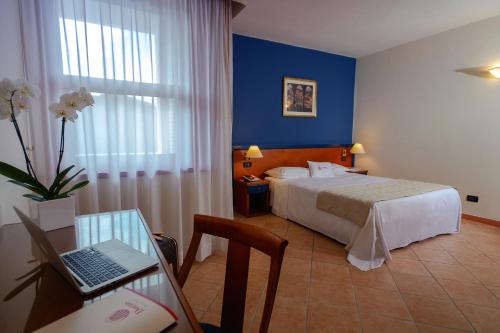 um quarto de hotel com uma cama e uma secretária com um computador portátil em DOMUS Grand Hotel em Rende