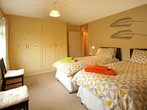 a bedroom with two beds and a chair at Mor Edrin in Criccieth