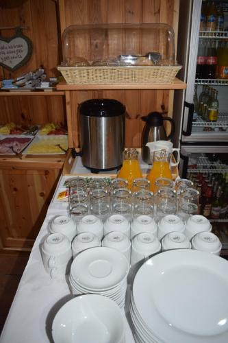 a counter with white plates and glasses on a counter top at Penzion Sabina in Vernár