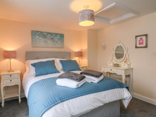 a bedroom with a large bed with blue and white sheets at Cedarwood Cottage in Winkleigh