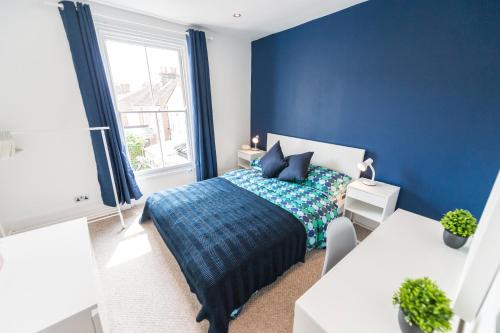 niebieska sypialnia z łóżkiem i oknem w obiekcie St Stephens Road Apartment w mieście Norwich