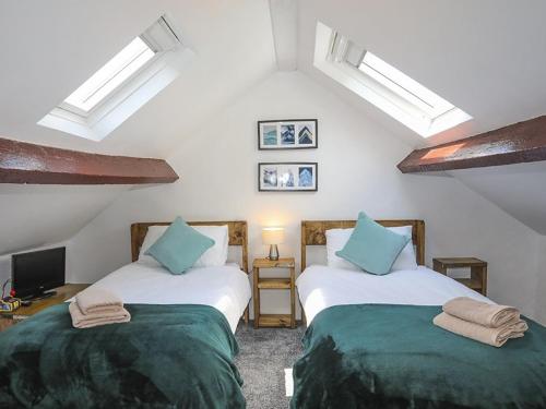 two beds in a room with white walls and blue pillows at Tan Meredydd in Nantlle