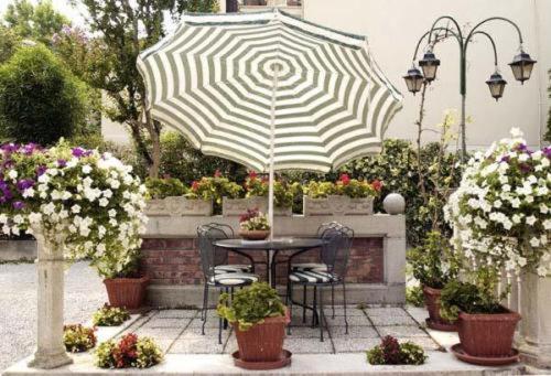 a table and chairs under an umbrella in a garden at Villa Albertina in Venice-Lido