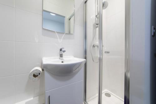 a white bathroom with a sink and a shower at The Norna in Cambridge