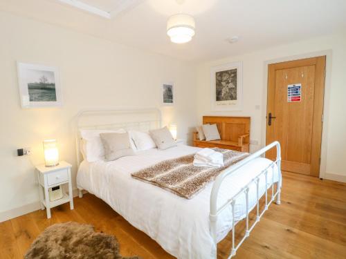 a bedroom with a white bed and a wooden floor at Shippon Barn in Yeovil