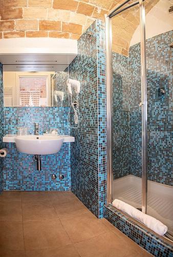 a blue tiled bathroom with a sink and a shower at Antico Borgo Chieti in Chieti
