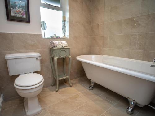 a bathroom with a toilet and a tub and a sink at Maes y Cregyn in Llanallgo