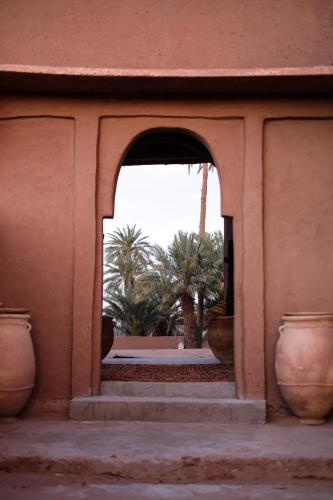 an archway in a building with palm trees in the background at Kasbah Aitisfoul in Tagounite