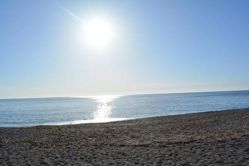 a beach with the sun shining on the water at Limeri Traditional Guest House in Monólithos