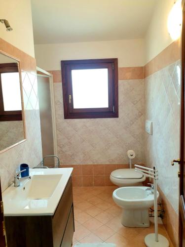 a bathroom with a sink and a toilet and a window at Residence Le Ginestre / Ataras in Porto San Paolo
