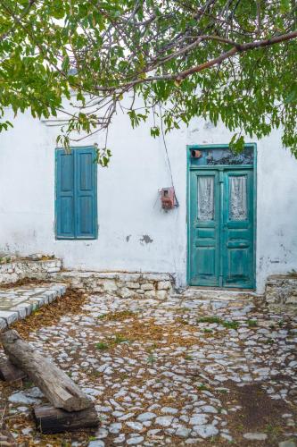 a white building with a green door and window at Limeri Traditional Guest House in Monólithos