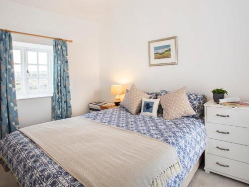 a bedroom with a bed and a dresser and a window at Mwythus in Rhoscolyn