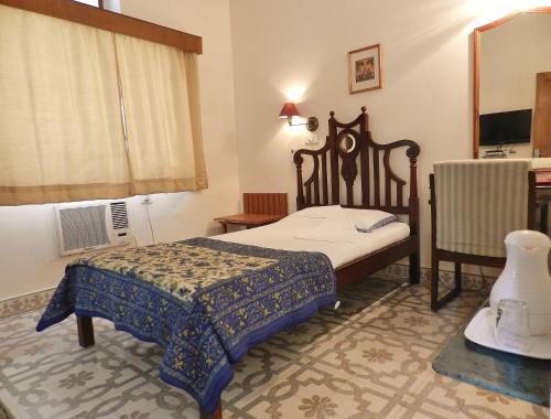 a small bedroom with a bed and a mirror at Hotel Arya Niwas in Jaipur