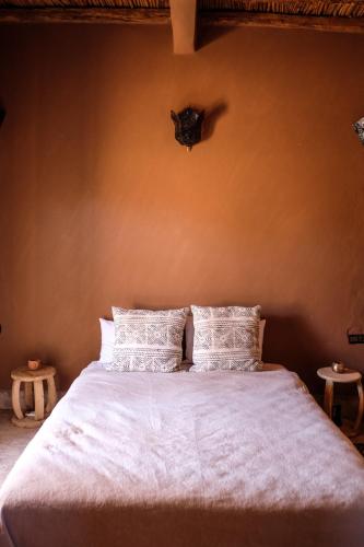 a bedroom with a bed with white sheets and pillows at Kasbah Aitisfoul in Tagounite
