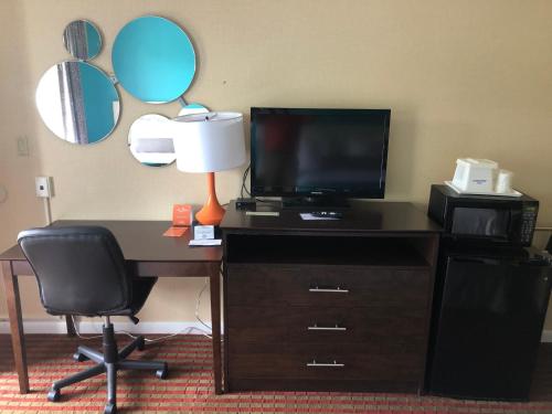 a desk with a television and a lamp on it at Howard Johnson by Wyndham Rocky Hill in Rocky Hill