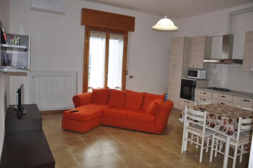 a living room with an orange couch and a kitchen at GiaLoSa Biker House in Villa Verucchio
