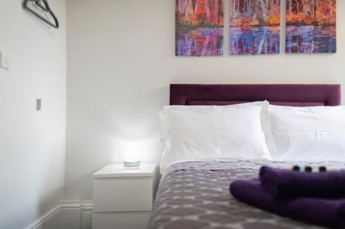 a bed with white pillows and a purple blanket at The Norna in Cambridge