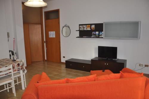 a living room with an orange couch and a tv at GiaLoSa Biker House in Villa Verucchio