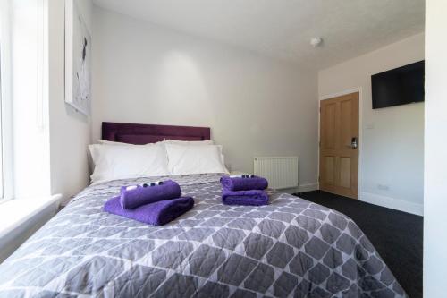 a bedroom with a large bed with purple pillows on it at The Norna in Cambridge