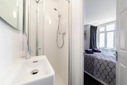 a white bathroom with a shower and a sink at The Norna in Cambridge